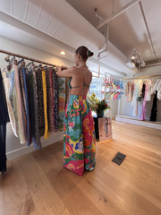 Woman in a colorful tropical outfit browsing clothing racks in a boutique.